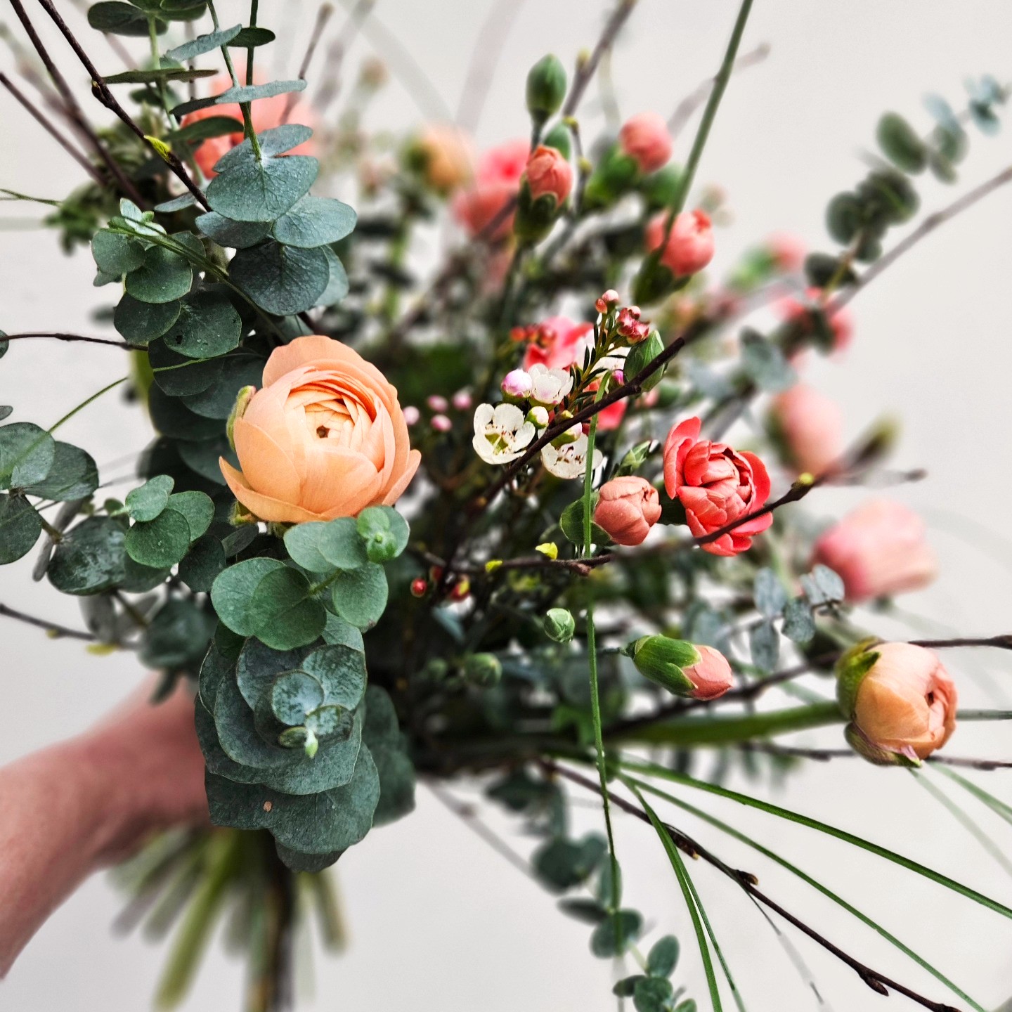 Luftig og vild buket bundet med ranunkler, grene og eukalyptus. 