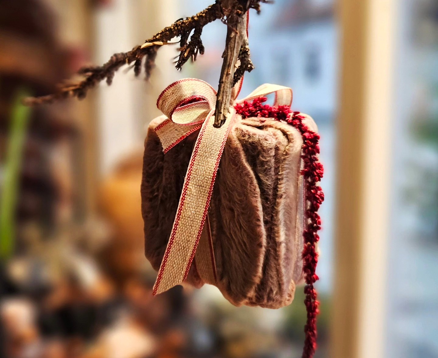 Lille julepakke med pels og sløjfe hænger fra en grangren. 
